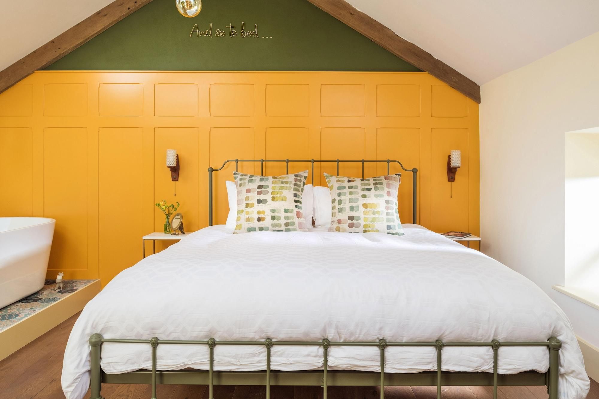 A bedroom with a metal bed frame, a white bedspread, and two wall-mounted lamps.