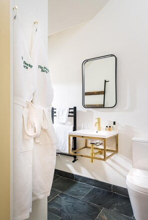 Ein modernes Badezimmer mit einer weißen Badewanne, einem goldfarbenen Waschtisch und einem schwarzen Spiegel.