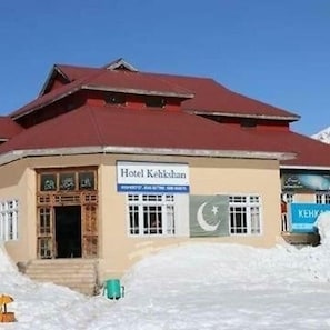 A building with a sign reading 'Hotel Kehkeshan' and a flag with a crescent and star.