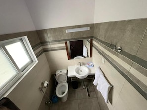 Un baño pequeño con inodoro, lavamanos y ventana.