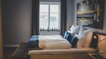 Ein Schlafzimmer mit einem Bett, Kissen, einem Fenster mit Flaschen und einem Gemälde an der Wand.