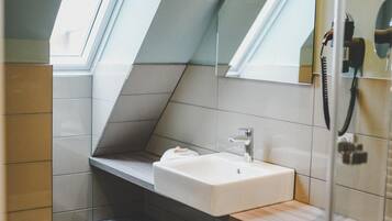 Ein modernes Badezimmer mit Dachfenster, Waschbecken, Spiegel und Toilette.
