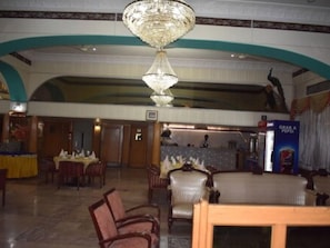 A spacious lobby with a grand chandelier, multiple dining areas, and a Pepsi vending machine. - Hotel De Mall (Rawalpindi)