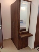 Un armario con espejo, una estantería pequeña y una puerta con pomo.