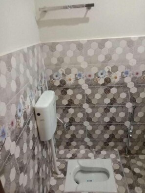 A bathroom with a toilet, a hand dryer, and a shower. - Ntp Palace Hotel (Lahore)