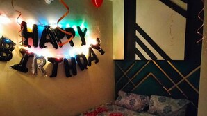 Een kamer met een bed, een muur met een 'HAPPY BIRTHDAY' decoratie en een kamerbreed tapijt met een patroon.
