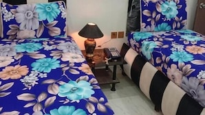 Een hotelkamer met twee bedden, een nachtkastje, een lamp, een spiegel en een deur.