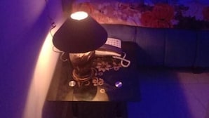 Een kamer met een bed, een nachtkastje met een lamp en een stopcontact.