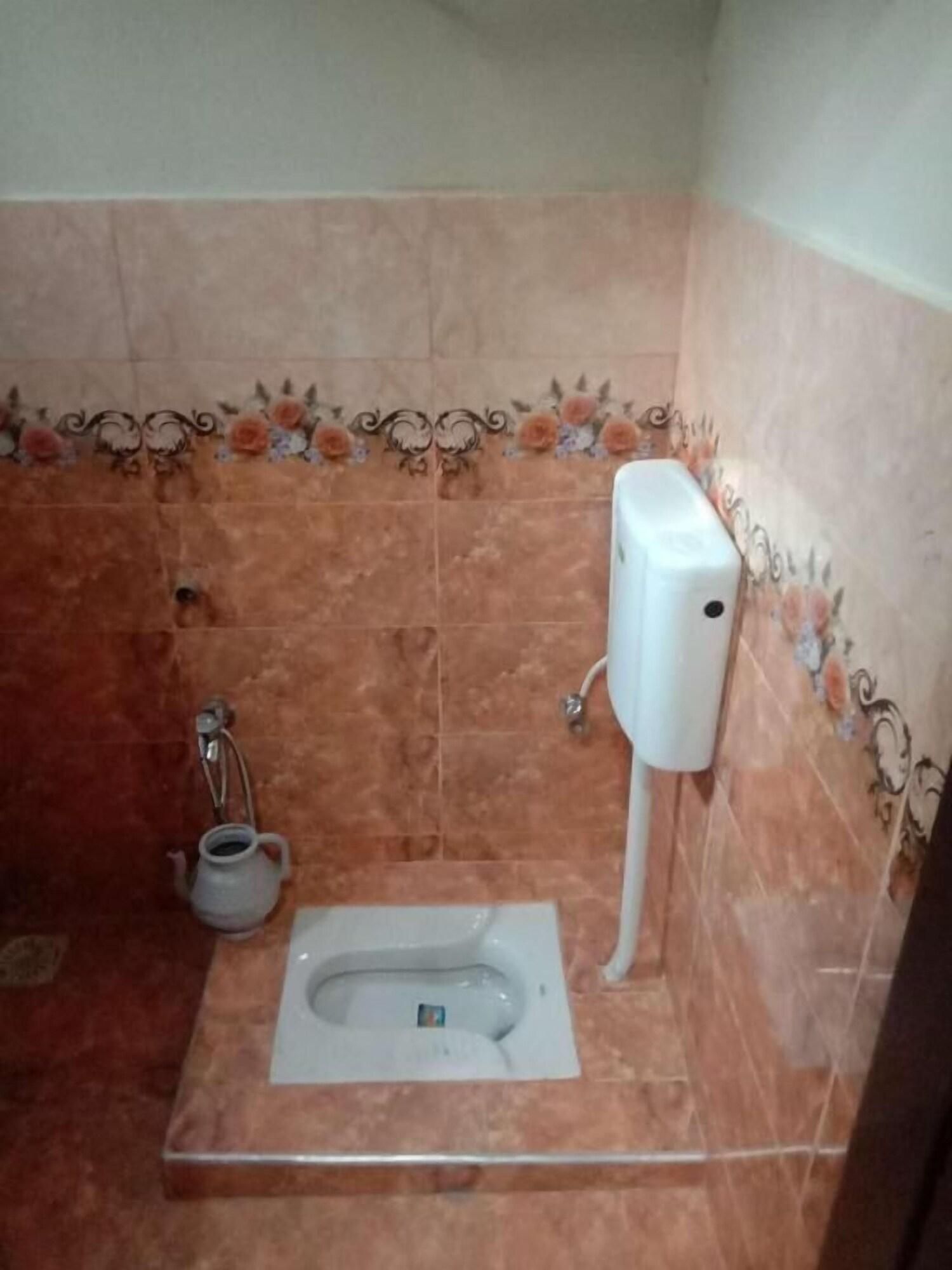 Une petite salle de bain équipée de toilettes, d’un sèche-mains et d’une fontaine à eau.