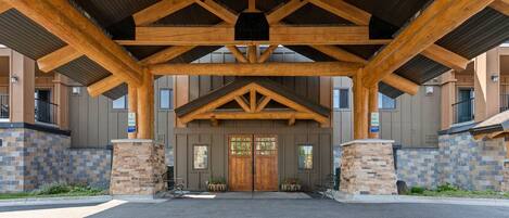 A building entrance with a wooden overhang, stone pillars, and a double door.