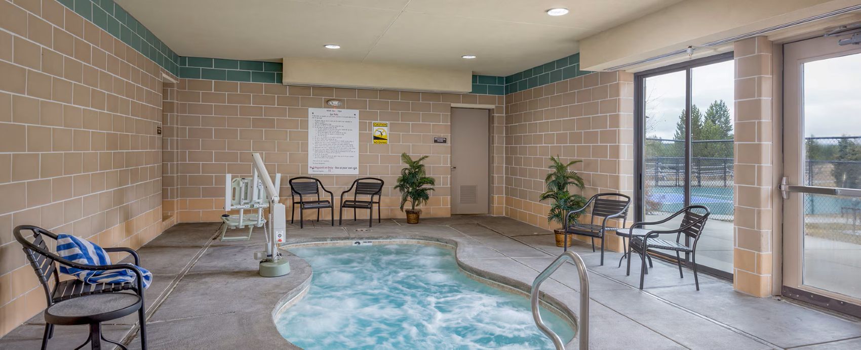 A spa area with a hot tub, seating, and a view through a glass door.