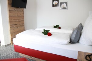 Una cama con ropa de cama blanca, un cabecero rojo y una almohada gris.