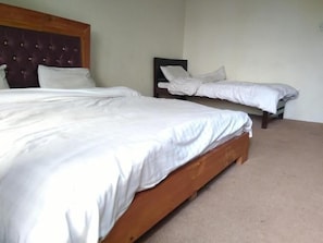 A bedroom with two single beds, a wooden headboard, and a carpeted floor.