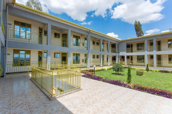 Un edificio de varios pisos con balcones, un patio interior y suelo de baldosas.