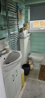 Un baño con lavamanos blanco, inodoro, zona de ducha y ventana con vistas.