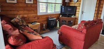 Una sala acogedora con un sofá rojo, un televisor y un mueble pequeño.