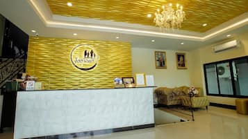 A reception area with a modern design, featuring a reception desk, a chandelier, and a sofa.