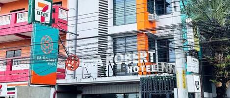 A hotel with a prominent sign, multiple floors, and a parking area with cars.