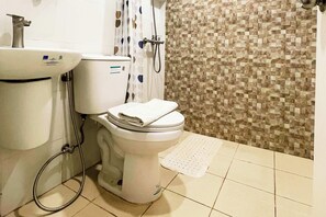 A bathroom with a toilet, sink, shower, and tiled floor. - Lea Robert Hotel Angeles Pampanga (Angeles City)