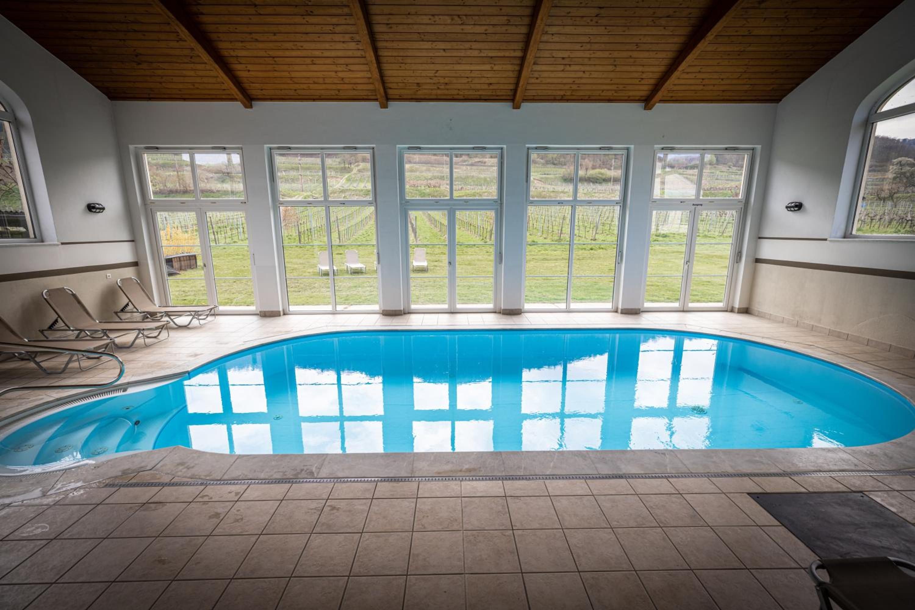 Una piscina con vistas a un viñedo a través de amplias ventanas.