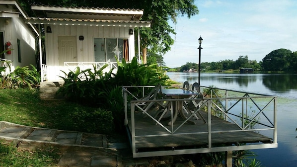 A lakeside building with a dock and a table with chairs. - Hadsaisuay Resort And Homestay (Kanchanaburi)