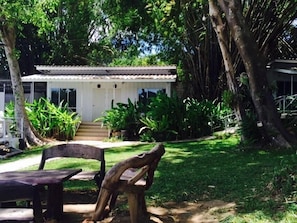 A small house with a porch, surrounded by lush greenery and trees. - Hadsaisuay Resort And Homestay (Kanchanaburi)