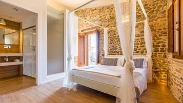 Ein Schlafzimmer mit Steinwand, einem Himmelbett und einem Badezimmer mit Duschkabine.