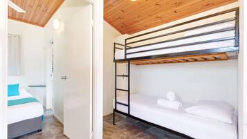 Una habitación con literas, una puerta y un baño con cortina de ducha.