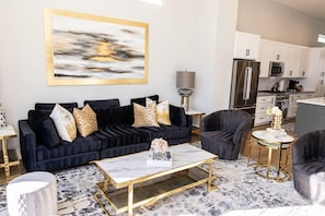 A modern living room with a dark blue sofa, a gold-framed coffee table, and a minimalist decor style.