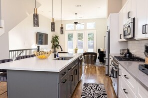 A modern kitchen with a large island, stainless steel appliances, and pendant lighting.