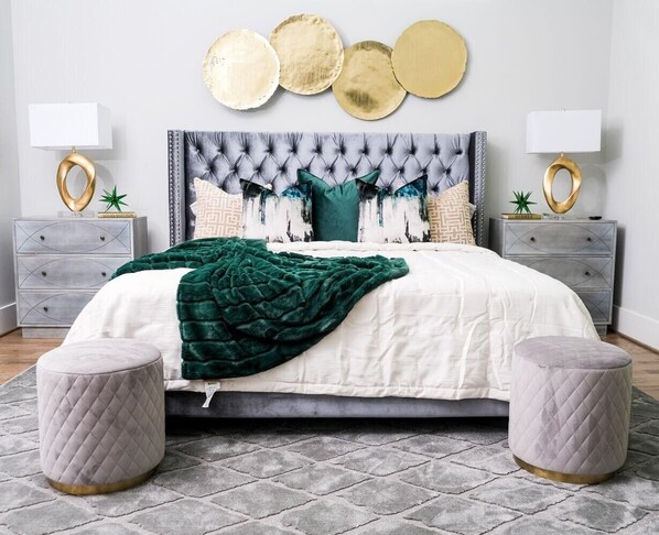 A bed with a tufted headboard, two bedside tables with lamps, and a grey patterned rug.