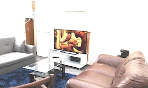 A living room with a flat-screen TV, a sofa, a coffee table, and a leather armchair.