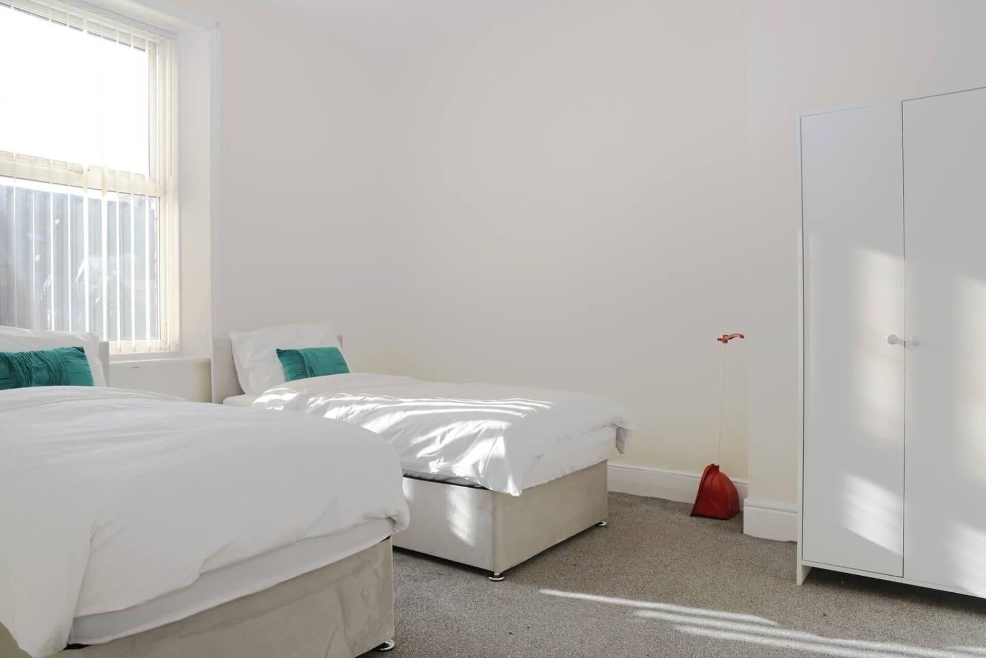 Une chambre avec deux lits, une armoire et une fenêtre.
