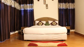 Una cama con cabecera de madera, dos almohadas, una mesita de noche y una alfombra roja y beige.