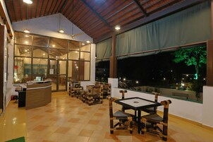 Un restaurante con suelo a cuadros, muebles de madera y grandes ventanales que dan a una vista nocturna.