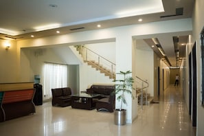 A modern hotel lobby with a staircase, a seating area, and a water dispenser. - Hotel Days Inn Two (Lahore)