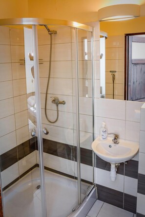 Un baño moderno con ducha envuelta en vidrio, un lavamanos blanco y un espejo.