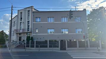 Un edificio residencial de varios pisos con techo plano, entrada porticada y paso de peatones.
