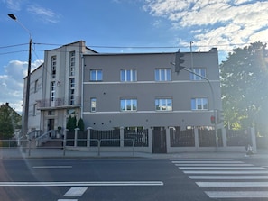 Un edificio residencial de varios pisos con techo plano, entrada porticada y paso de peatones.