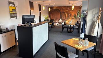 Un vestíbulo de hotel con mostrador de recepción, zona de estar y un mural.