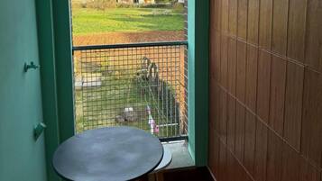 A balcony with a view of a residential area, a small table, and a chair.