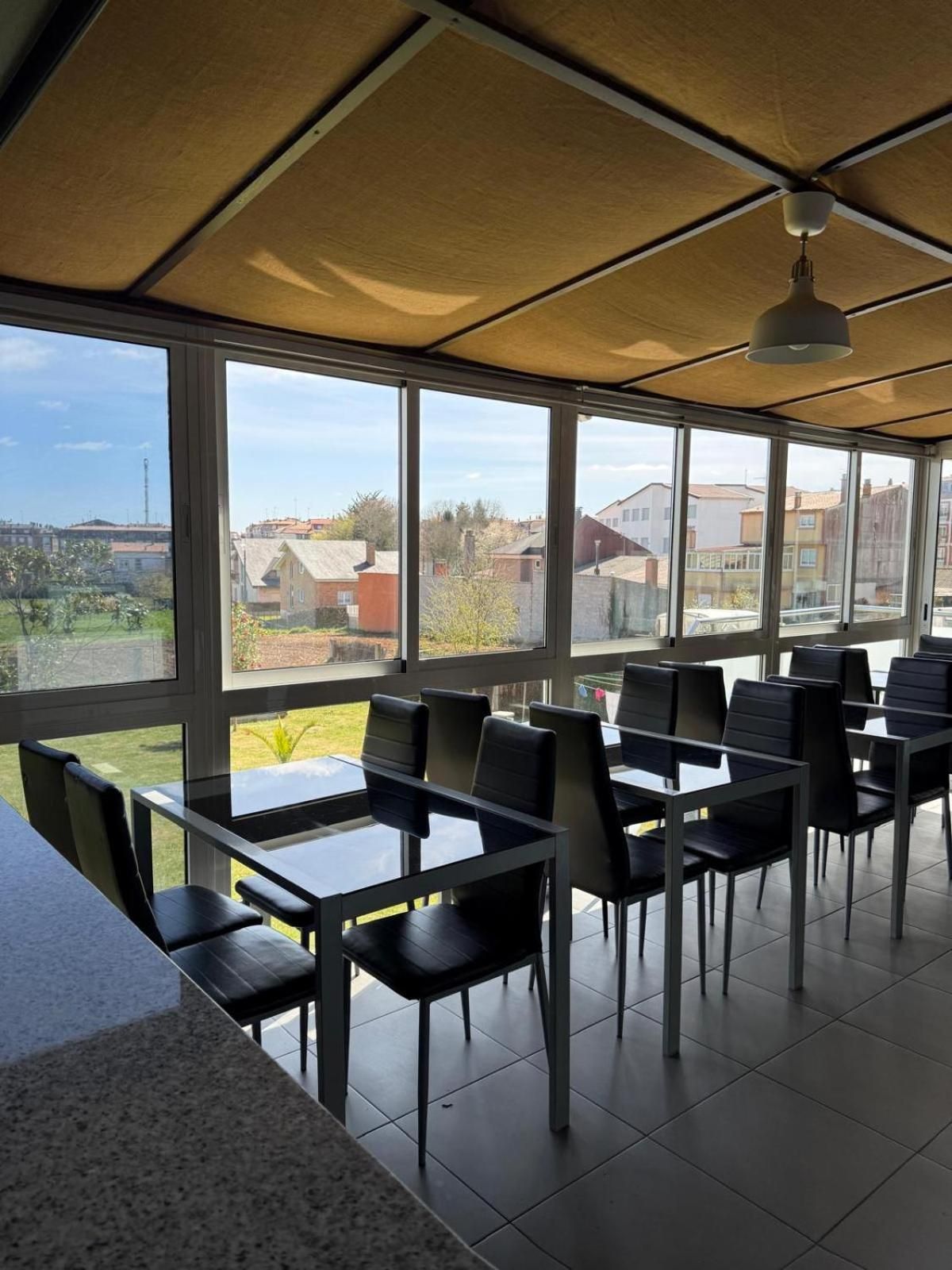 A dining area with tables and chairs, large windows, and a ceiling fan.