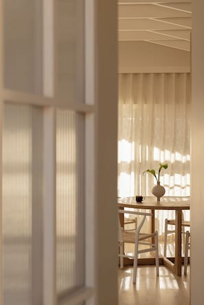 Ein Zimmer mit einem Holztisch, Stühlen und einer Blumenvase.