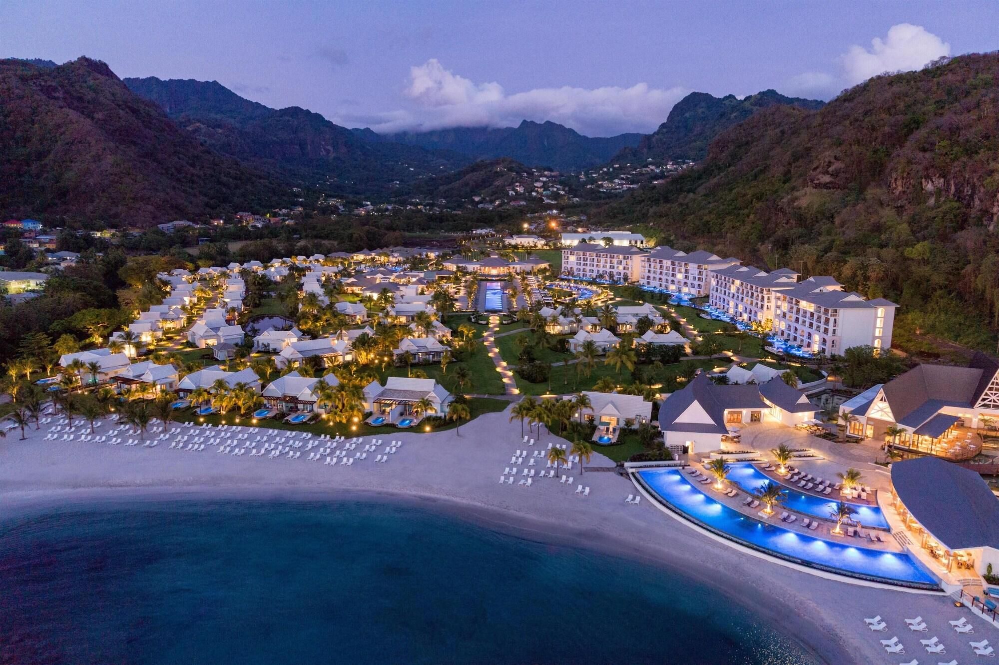 Ein Resort mit mehreren Gebäuden, einem großen Poolbereich und einem Strand.