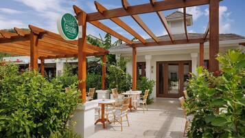 Eine Terrasse mit Holz-Pergola, Sitzgelegenheiten im Freien und einem Schild für 'Blum Jamaican Coffee'.