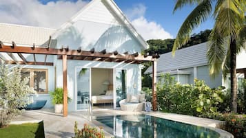 Ein modernes Haus mit Schwimmbad, überdachter Terrasse und üppiger Bepflanzung.