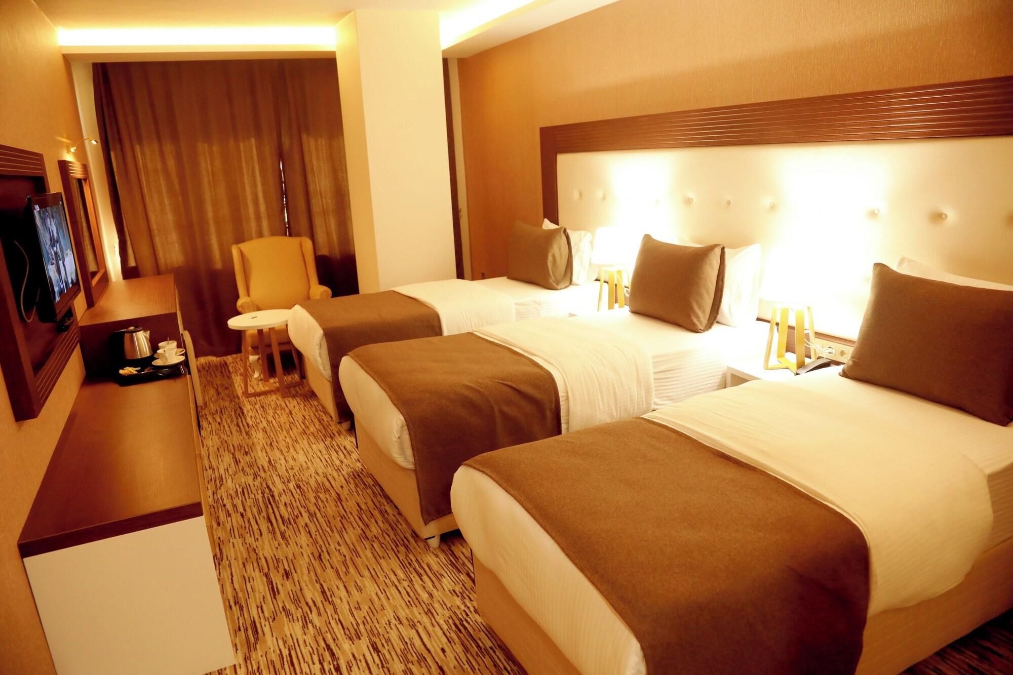 Ein Hotelzimmer mit zwei Betten, einem Fernseher, einem Sessel und einem kleinen Tisch mit Frühstücksgebäck.