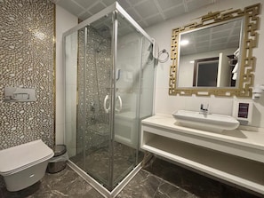A bathroom with a glass-enclosed shower, a white sink, and a decorative wall. - Van Life Hotel (Van)