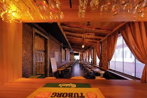 A long, narrow room with tables and chairs arranged for dining, wooden walls, and a view through large windows. - Van Life Hotel (Van)