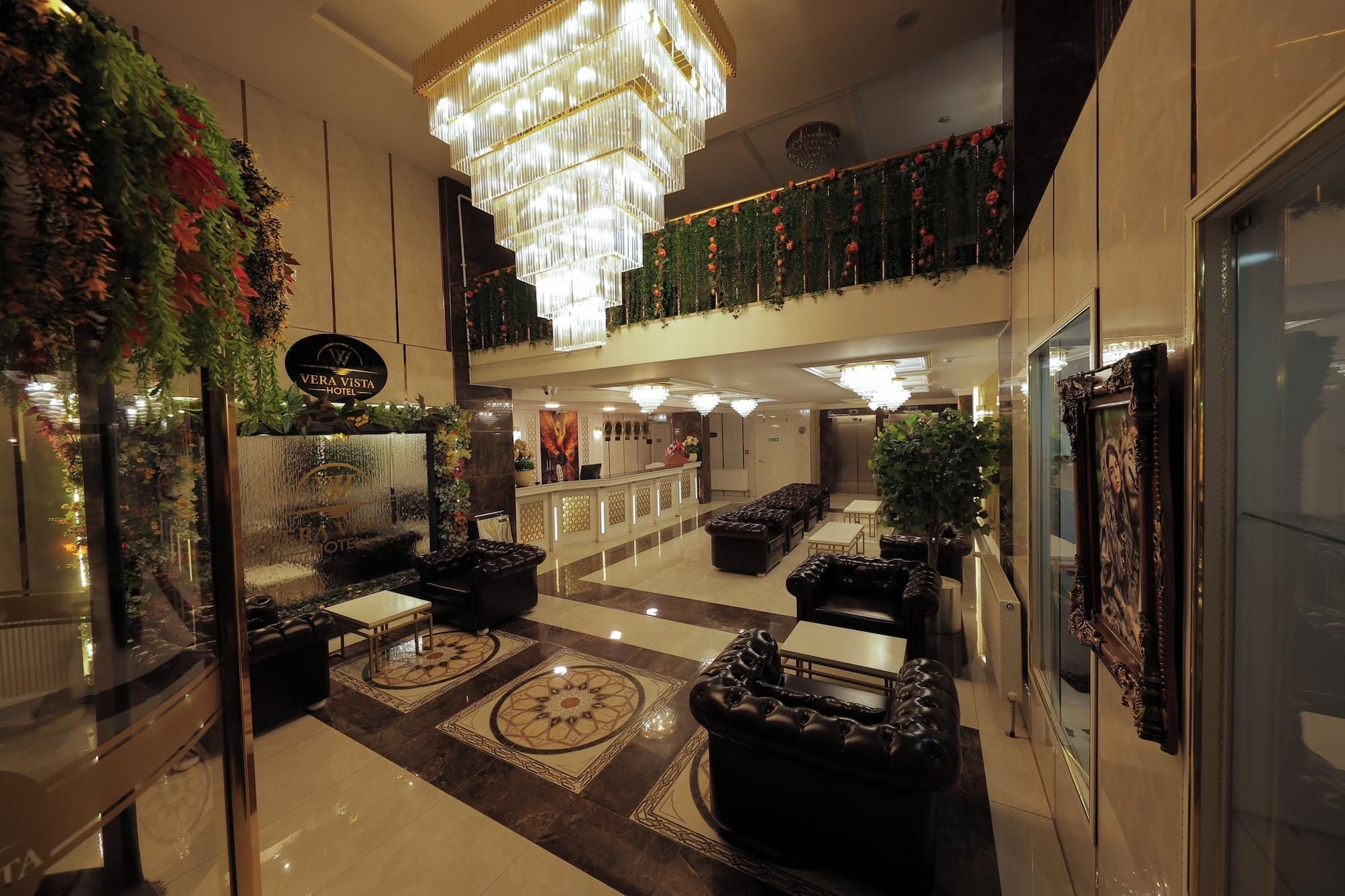 Eine Hotelhalle mit einer Rezeption, Sitzgelegenheiten, einem Kronleuchter und einer Wandverkleidung.